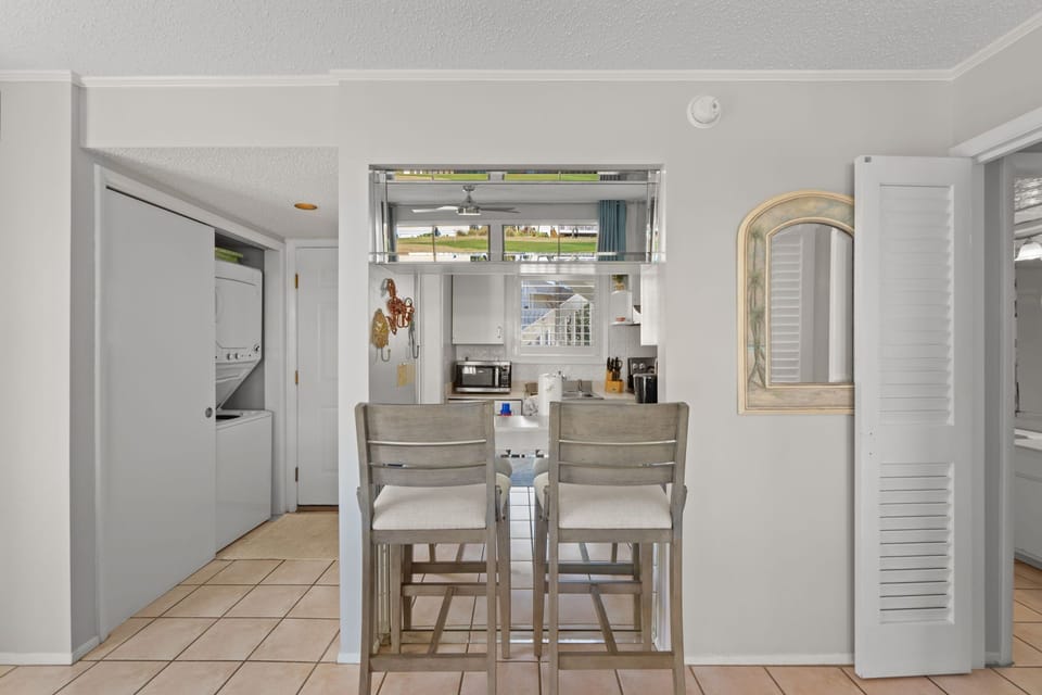 The breakfast bar offers additional seating for casual meals, snacks, or evening drinks, with an open pass-through design connecting the kitchen and living area for an easy, relaxed coastal feel.