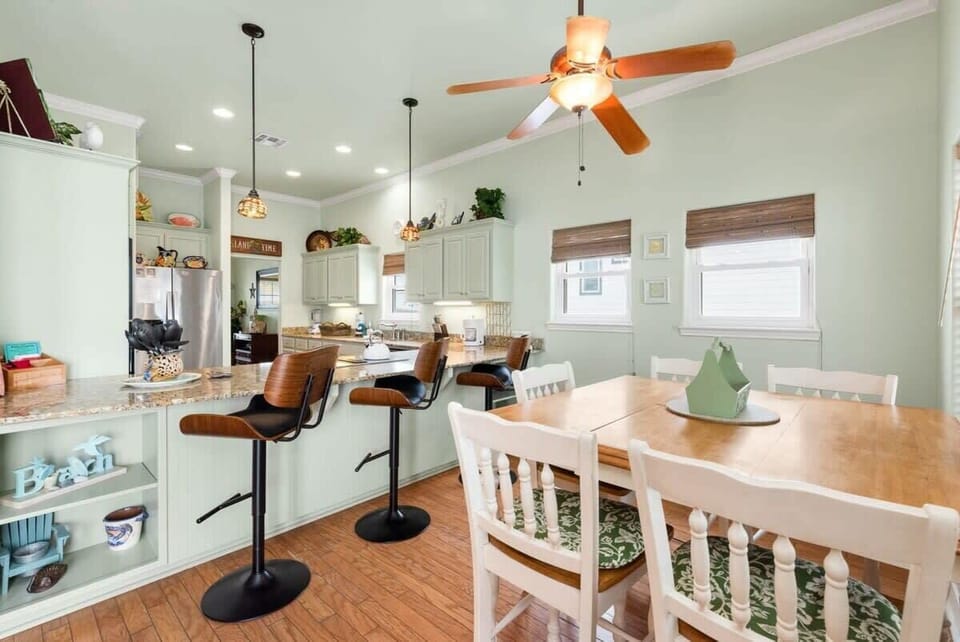 Dining area with white farmhouse table, spindle chairs, and breakfast bar