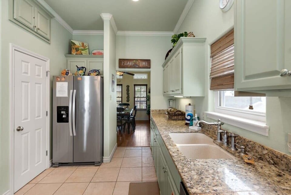 Kitchen with stainless steel fridge, granite counters, and Island Time sign