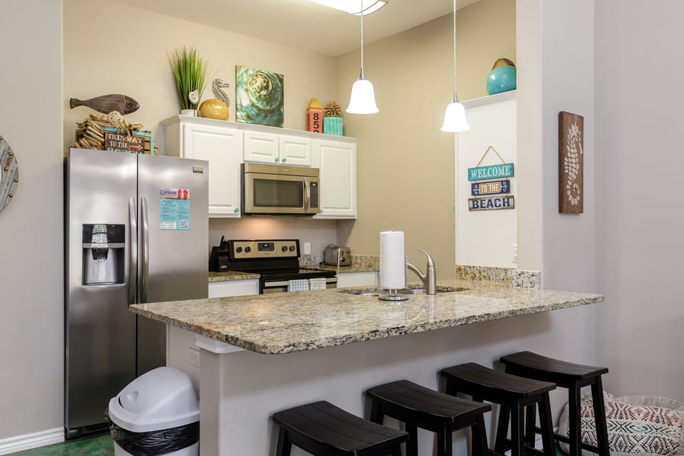 Prepare your favorite meals in this fully equipped kitchen featuring granite countertops, stainless steel appliances, and breakfast bar seating.
