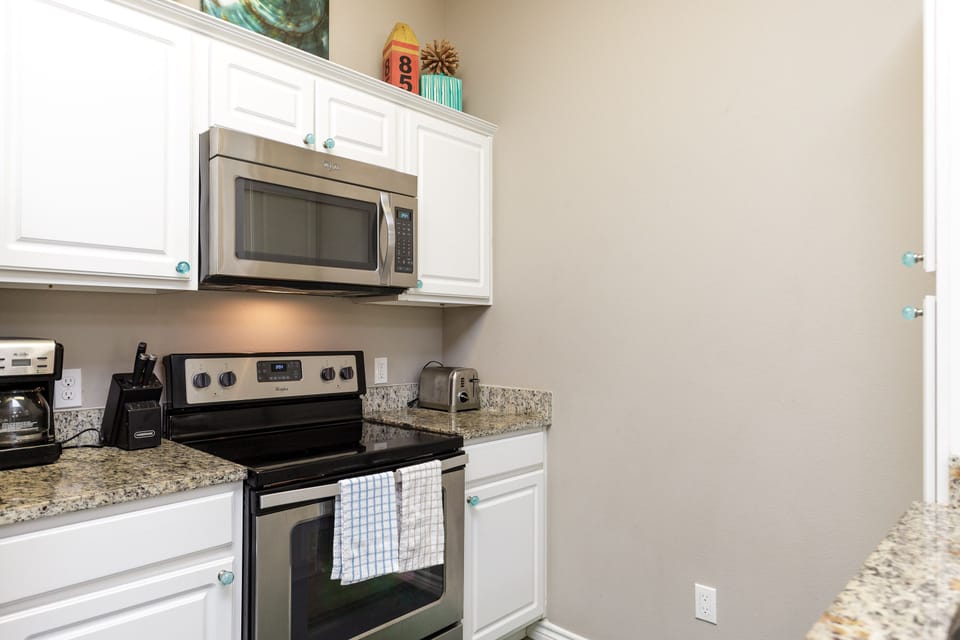 Your modern kitchen features granite countertops, stainless steel appliances, and crisp white cabinetry - perfect for preparing meals during your stay.
