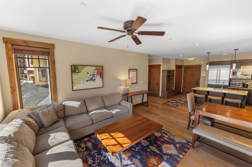 Relax in your spacious living area with plush sectional seating, warm wood accents, and an open kitchen perfect for gathering.