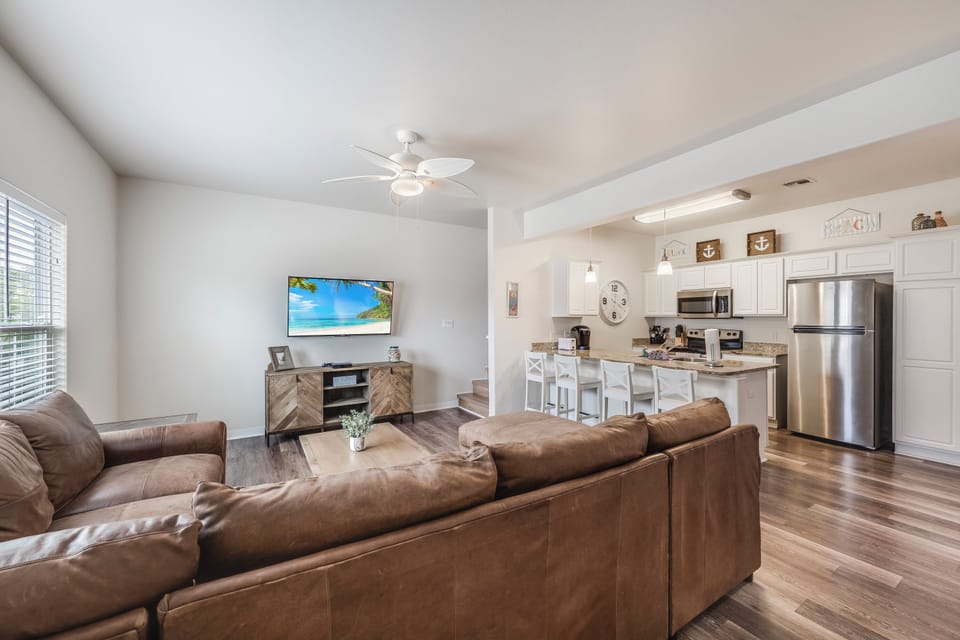 Relax in your open-concept living space with plush leather seating, modern kitchen, and coastal décor creating the perfect home base.