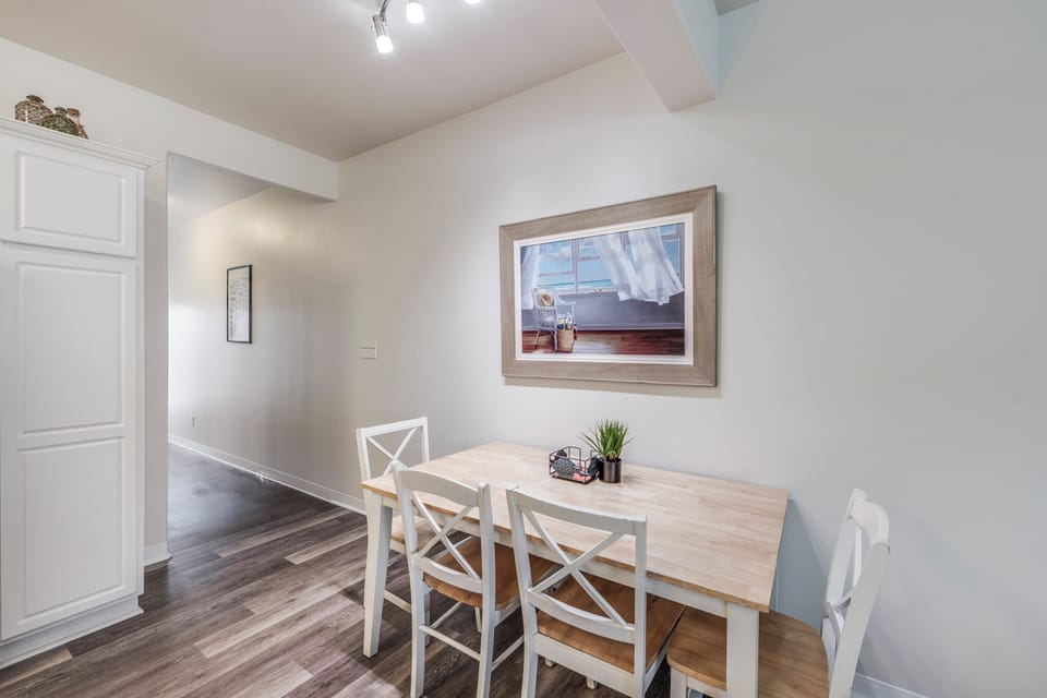 Your cozy dining nook awaits with warm wood tones and coastal-inspired artwork, perfect for intimate meals or morning coffee.