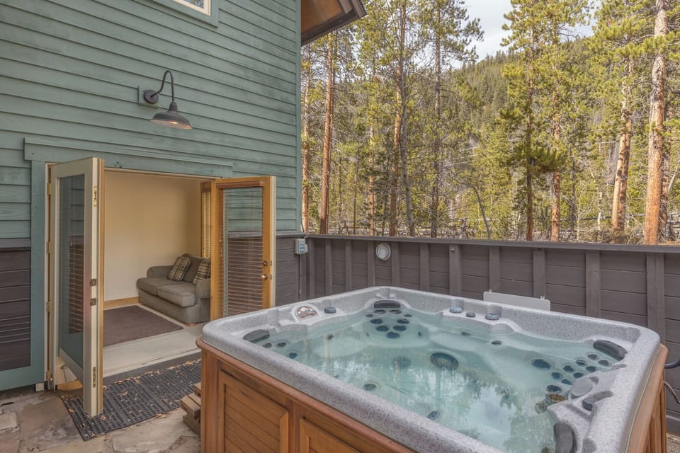 Step into your private sanctuary where bubbling jets invite relaxation beneath the forest canopy on this serene outdoor deck.