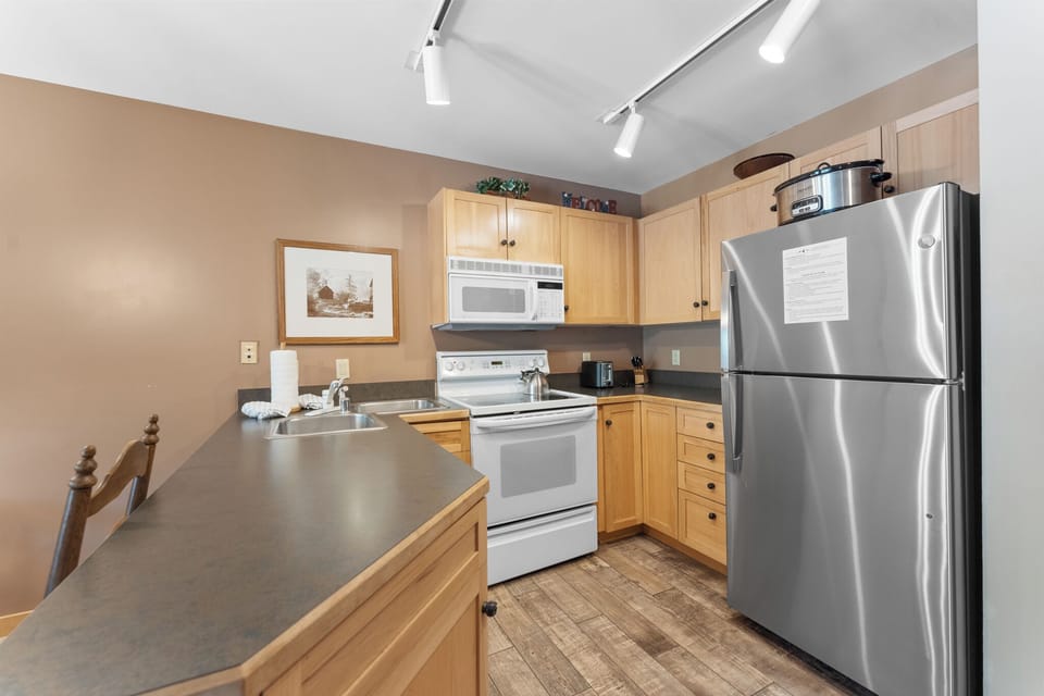 Your fully equipped kitchen features stainless steel appliances and warm wood cabinets, perfect for preparing home-cooked meals during your stay.