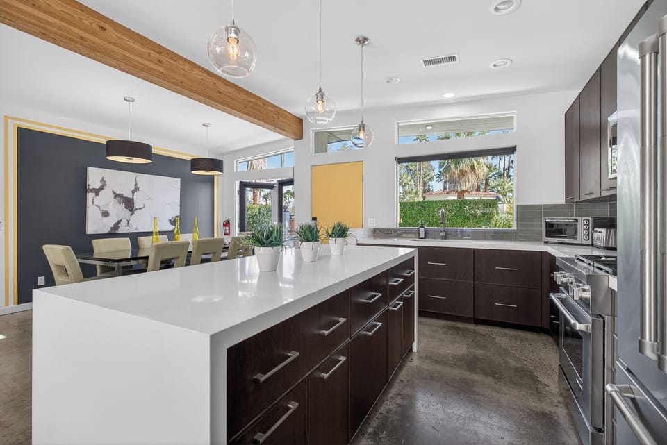 Cook meals with ease in this sleek modern kitchen featuring a spacious island and garden views through large windows.