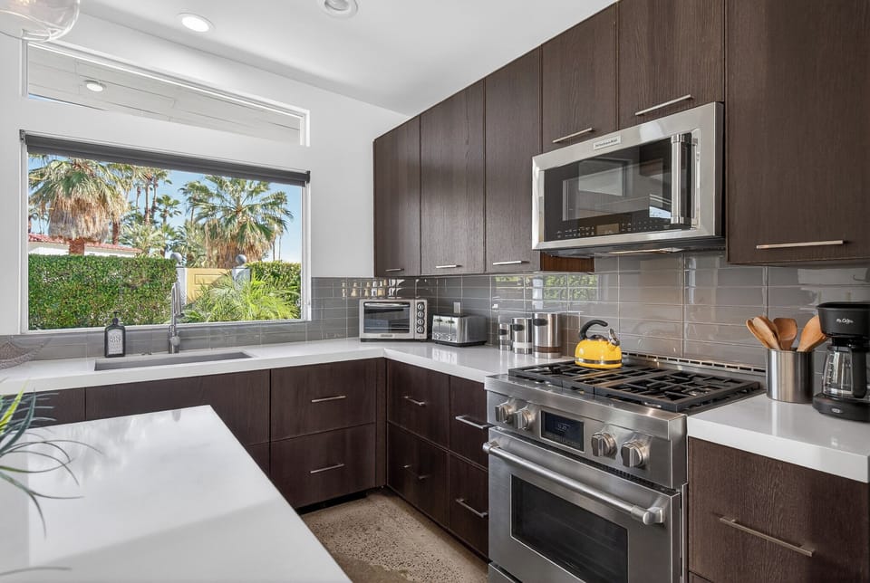 Your sleek modern kitchen awaits with stainless appliances and tropical views through the window.