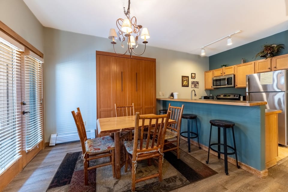 Your open dining and kitchen space features warm wood furnishings, elegant chandelier lighting, and a breakfast bar perfect for casual meals.