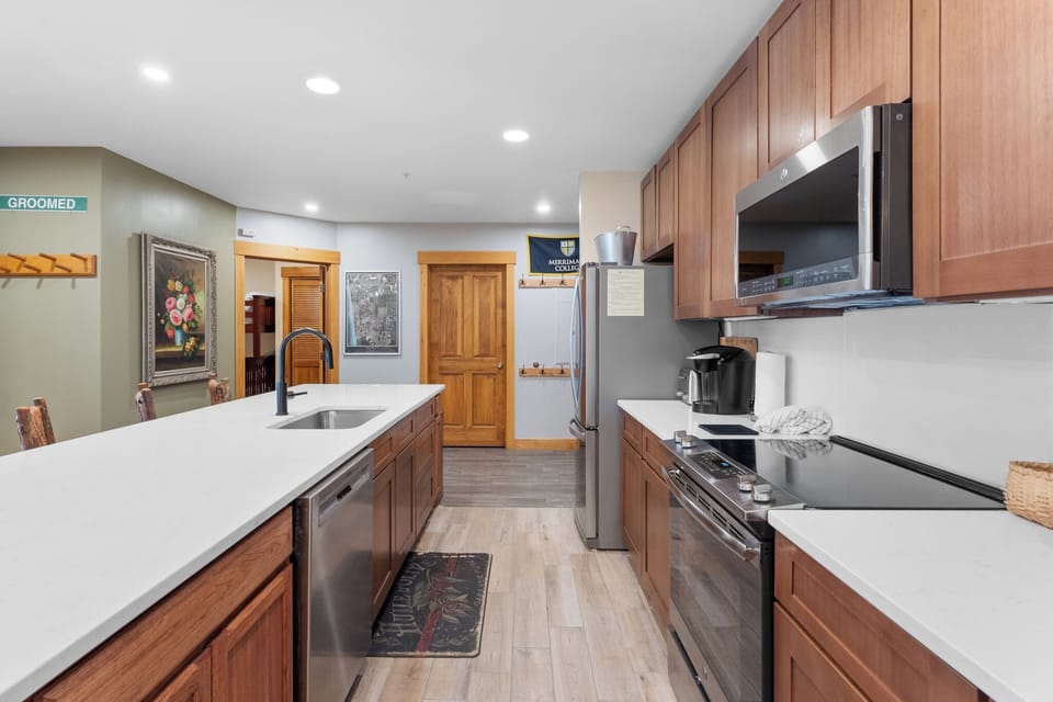 Your spacious modern kitchen features warm wood cabinetry, sleek white counters, and stainless steel appliances for all your culinary adventures.