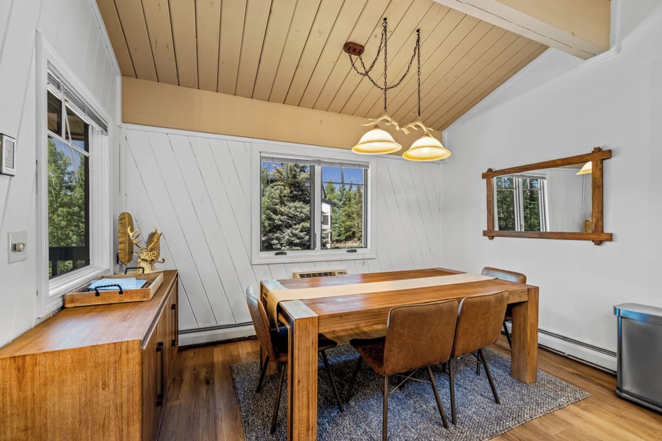 Gather around this handsome wood table for meals and laughter, warmed by natural light and the inviting glow of pendant fixtures overhead.
