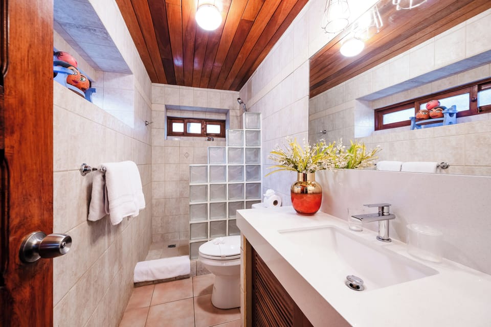 Full bathroom in Playa Langosta, Tamarindo Costa Rica vacation rental with toilet, sink, and shower. Bright and clean design offers comfort and convenience for family vacations, blending tropical style with practical amenities near the beach.