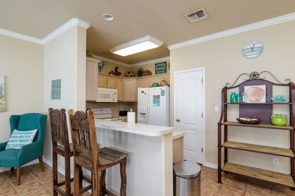 Your fully-equipped kitchen awaits with coastal charm, breakfast bar seating, and beach-themed touches that make meal prep feel like vacation.