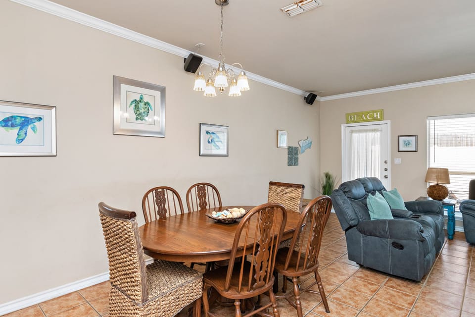 Gather around the warm wood dining table while you unwind in plush recliners, surrounded by cheerful coastal art.