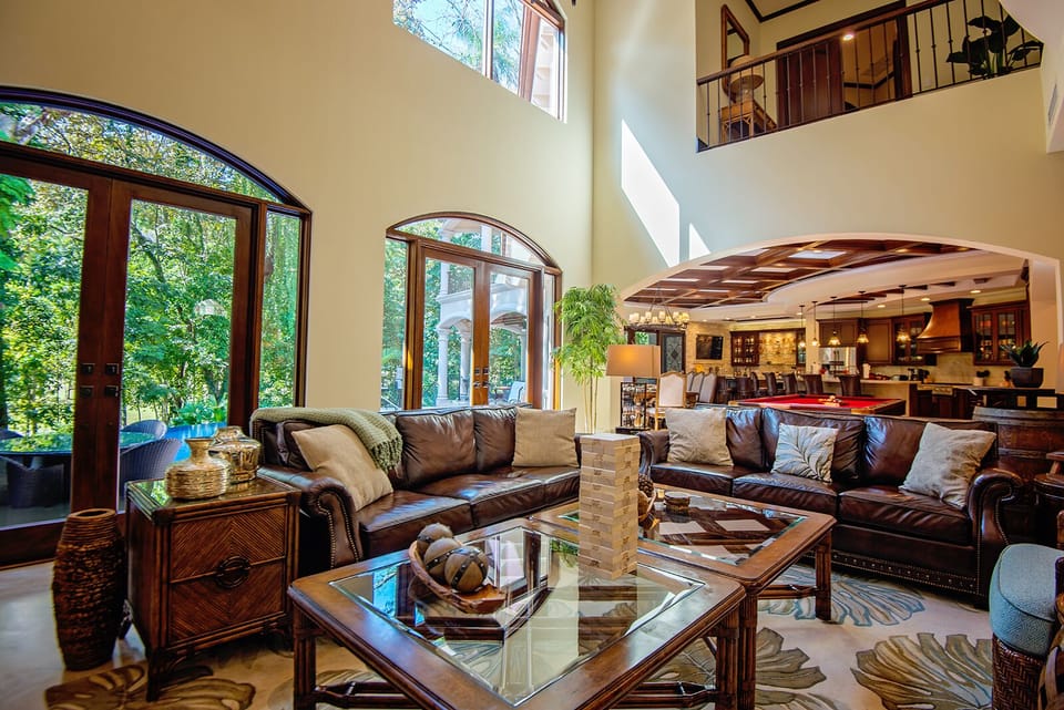 Living room area with large windows, with view to the garden, pool area and rainforest.