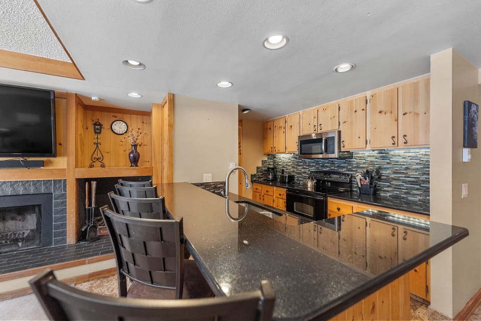 Your spacious kitchen features warm wood cabinets, granite counters, and a breakfast bar perfect for morning coffee or casual meals.