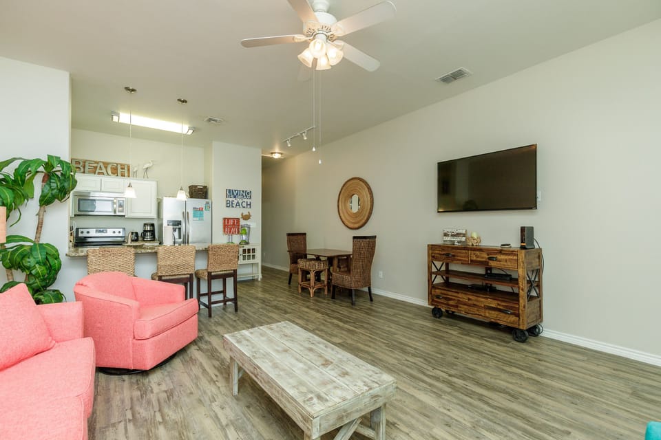Your bright open living area features coral seating, coastal decor, and modern amenities - perfect for relaxing after beach days.