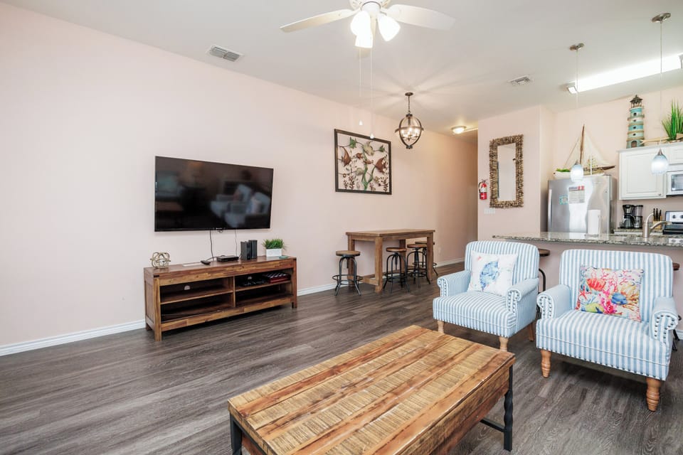 Unwind in your cozy living room featuring striped armchairs, rustic wood accents, and modern entertainment setup for perfect relaxation.