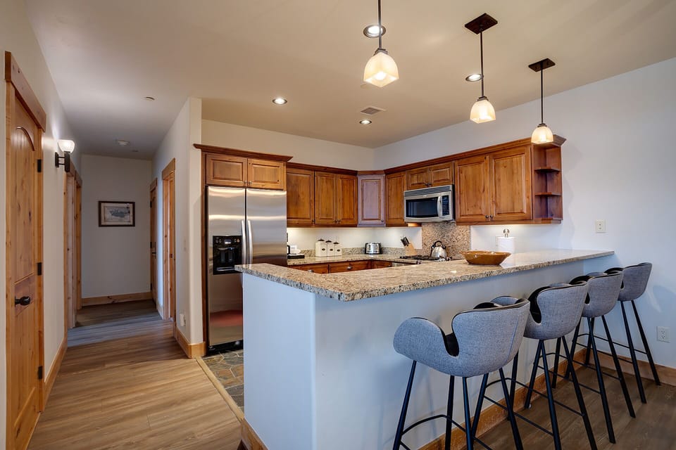 Your fully equipped kitchen features granite countertops, warm wood cabinetry, and a breakfast bar where you can gather for morning coffee.