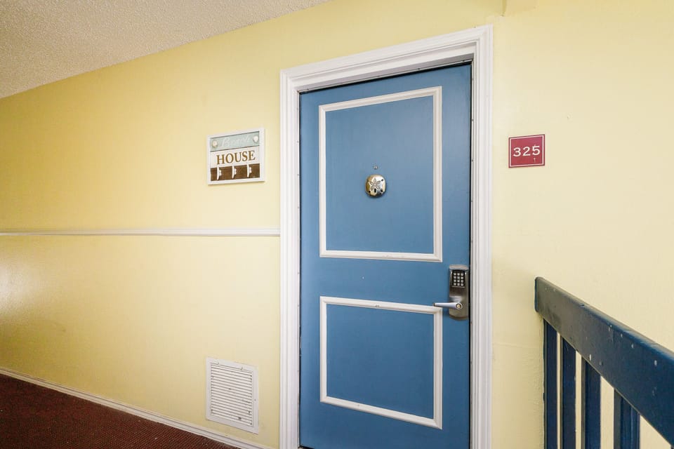 Your charming blue door awaits in this well-maintained hallway with clear room signage and secure keypad entry.