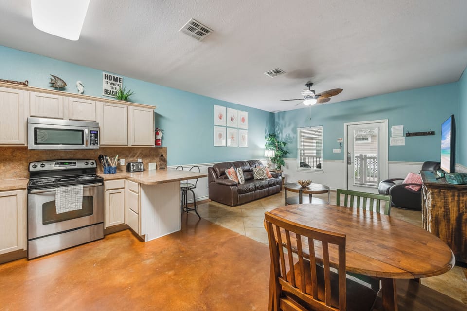 Relax in your open-concept space where calming blue walls and modern appliances create the perfect beach retreat atmosphere for unwinding.