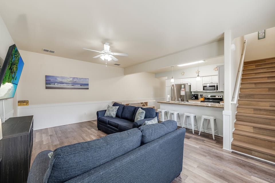 Relax in your open-concept space with plush seating, modern kitchen, and stylish coastal artwork creating the perfect home base.