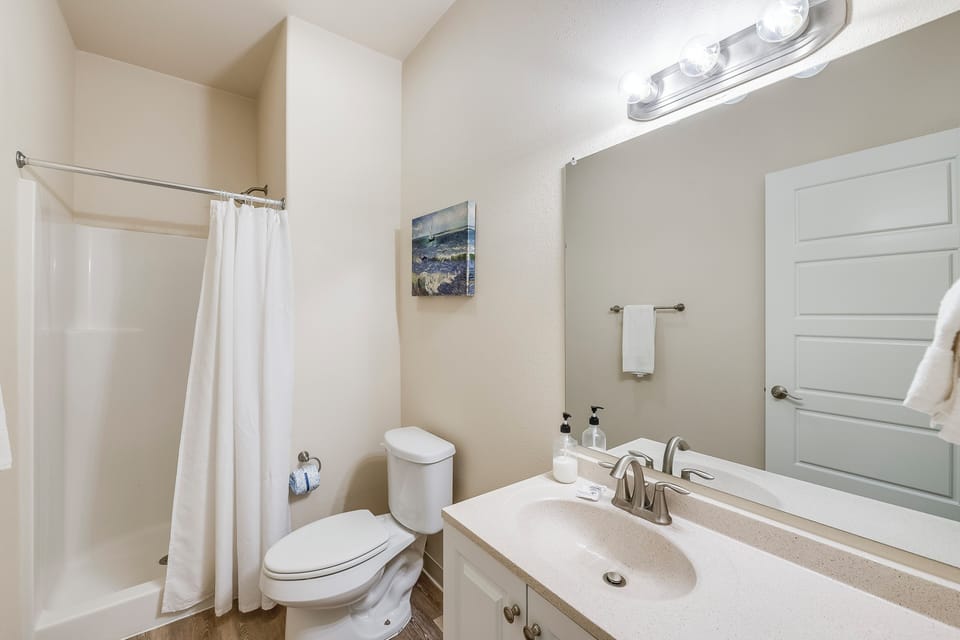 Fresh white towels await your arrival in this clean, well-lit bathroom with modern fixtures and thoughtful touches.