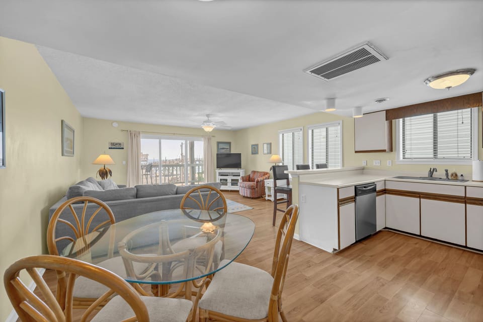 An open-concept living and kitchen area awaits, with comfortable seating, natural light through large windows, and a fully equipped kitchenette ready for your stay.
