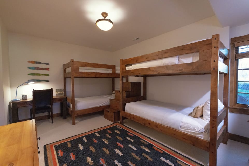 Your home away from home features cozy bunk beds perfect for families or friends, with crisp white linens and a cheerful workspace by the window where you can plan your adventures.
