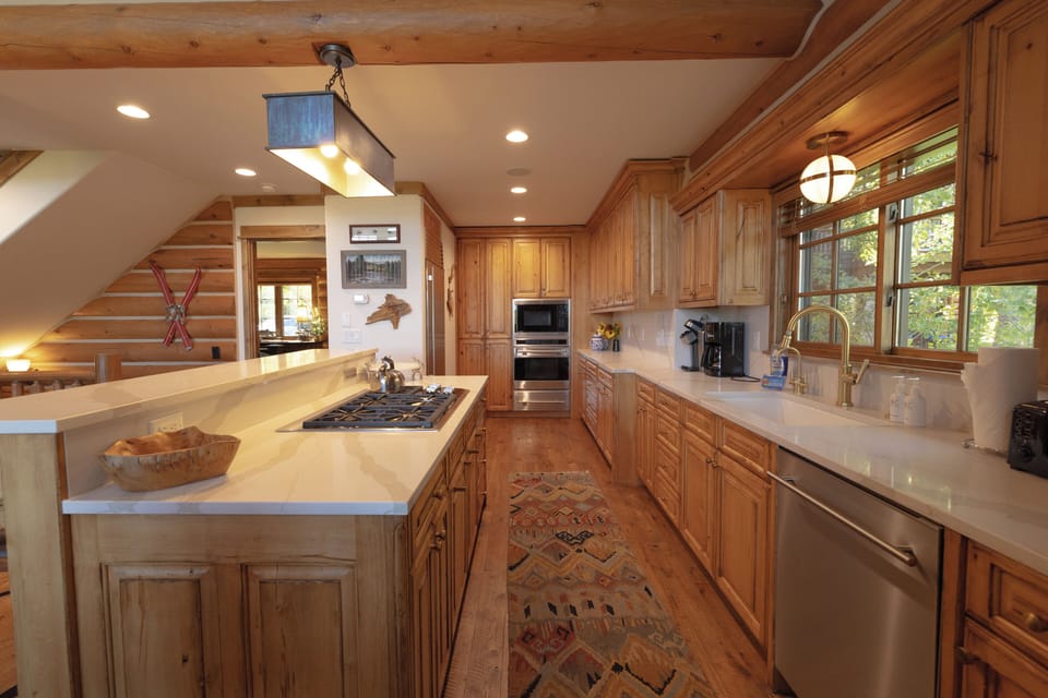 Your gourmet kitchen awaits with warm wood cabinetry, gleaming quartz counters, and a spacious island perfect for cooking together. Natural light streams through large windows as you prepare meals with top-tier appliances.