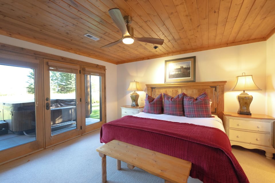 Drift off to sleep under stunning wood-beamed ceilings in your cozy retreat, where warm red linens and rustic charm create the perfect mountain getaway atmosphere.