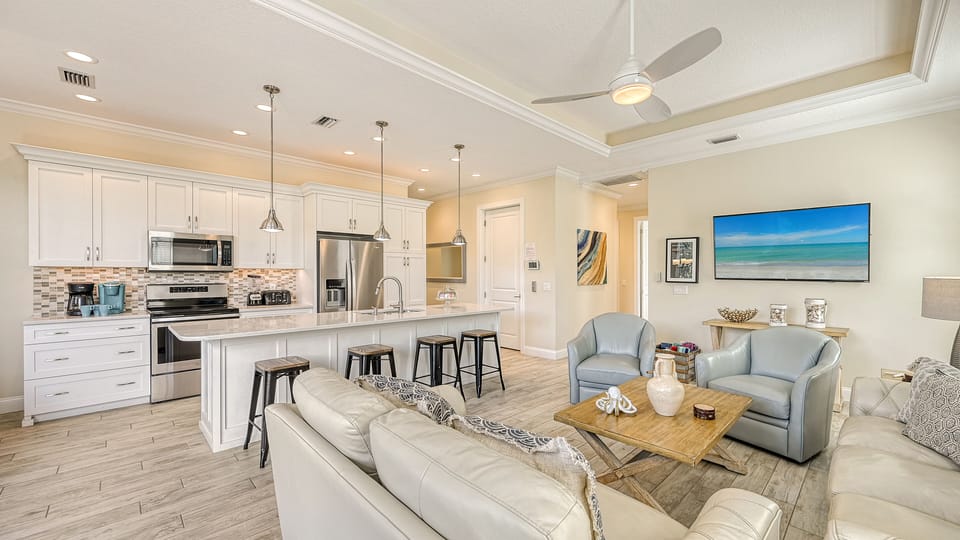 Bask in the open flow of this inviting space—where lively conversations start at the breakfast bar and cozy sofas await your unwind after a day in the sun.