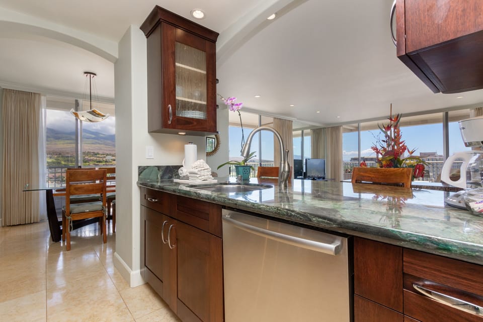 Step into your beautifully appointed kitchen featuring rich wood cabinetry, gleaming granite countertops, and stainless steel appliances. The open layout flows seamlessly to your dining and living spaces, all framed by floor-to-ceiling windows offering stu