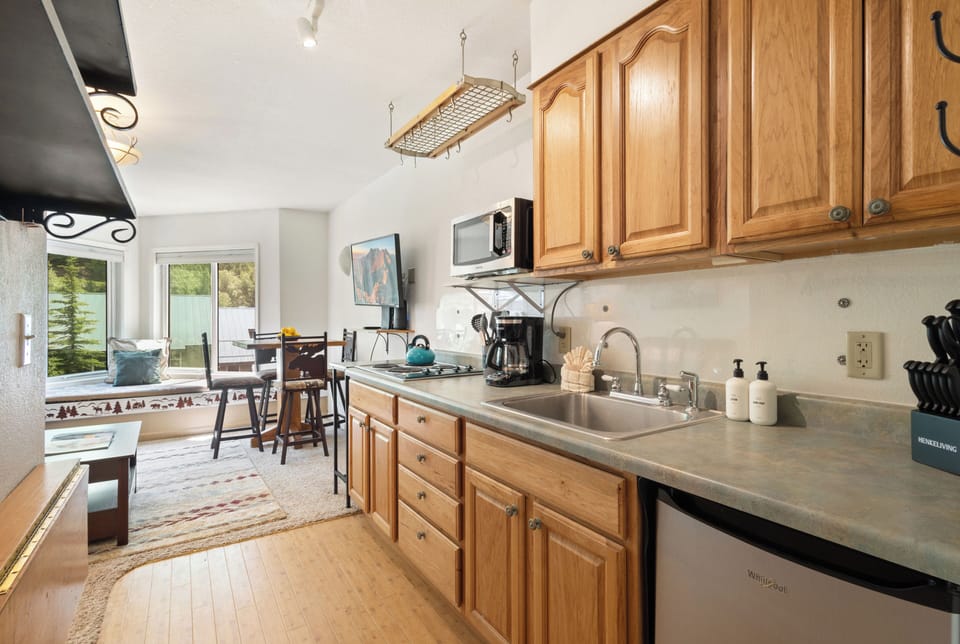 Galley kitchen with stove top and mini fridge.