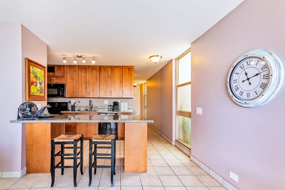 Gather around the breakfast bar in your fully equipped kitchen, where warm wood cabinetry and granite countertops invite you to prepare morning coffee or evening meals together.