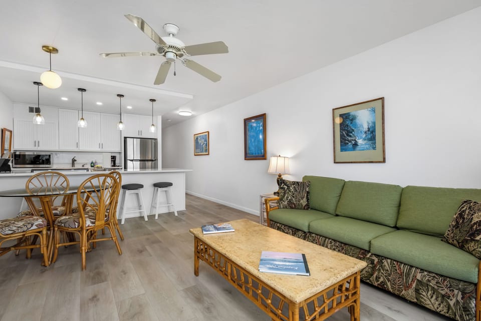 Settle into your spacious living area where tropical-inspired decor meets modern comfort. High ceilings and coastal artwork create a relaxing vibe, while the open kitchen invites you to gather with loved ones.