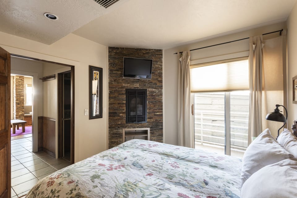 Sliding glass private balcony door in the bedroom, slatestone in-room fireplace and fireplace mounted flat screen TV