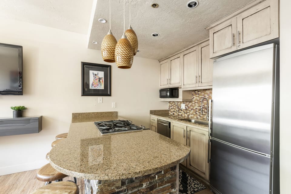 Fully equipped kitchen, granite countertops, gas burning range on the breakfast bar and stainless steel appliances