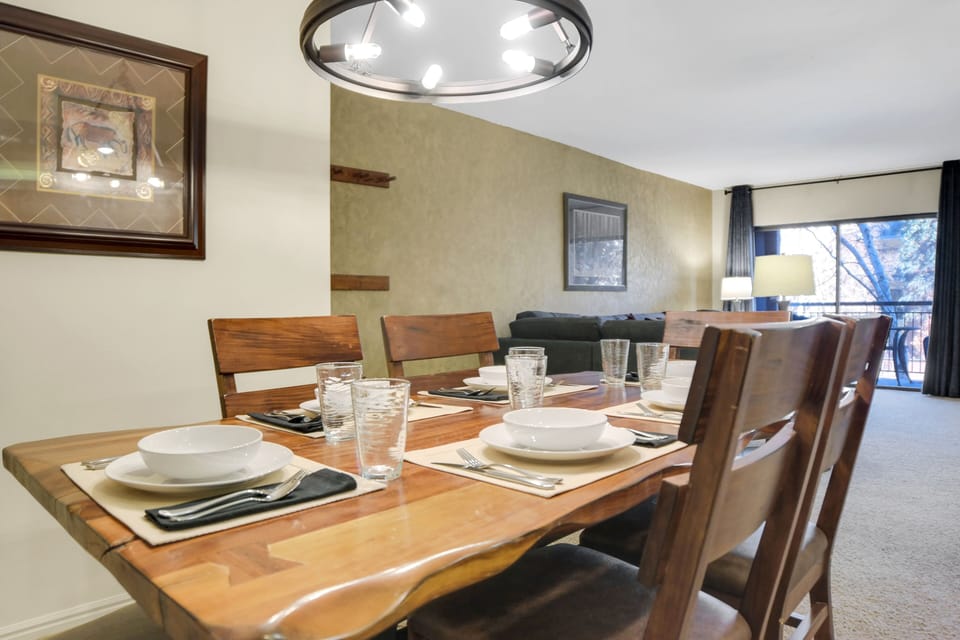 Park Station 122's dining room has a wood table, 6 chairs and place settings, and black circular chandelier.