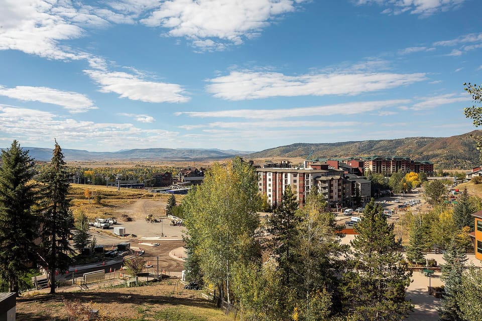Elevated mountain town view showcasing autumn foliage and residential buildings nestled in a scenic valley setting.