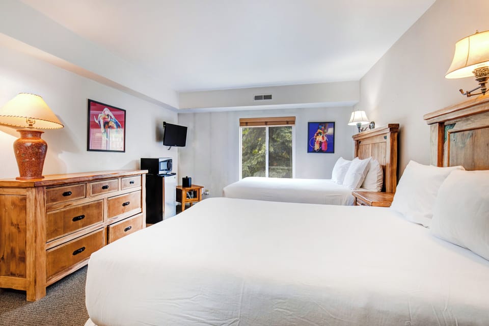 One of the bedrooms offer two queen beds with wooden furniture.