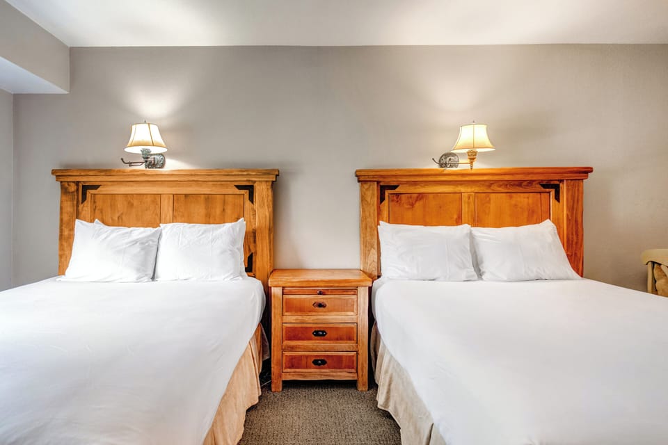 One of the bedrooms offer two queen beds with wooden furniture.