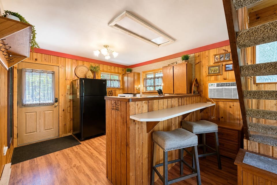 Step into your welcoming kitchen featuring warm wood finishes, a breakfast bar with seating for two, and all the essentials for preparing memorable meals during your stay.