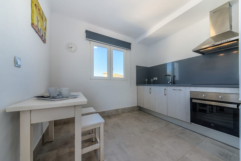 Countertop with sink, oven and ceramic hob and small table in the kitchen of Villa Fuente del Gallo in Villas Flamenco Beach in Conil