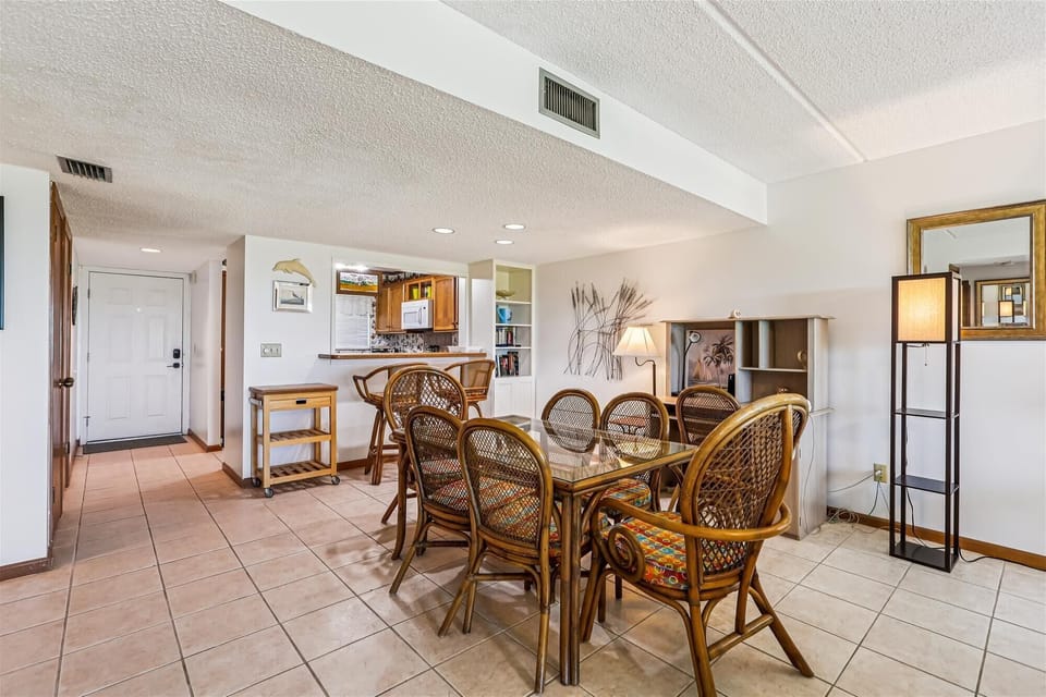 - Dining space with glass table, bamboo chairs, and warm lighting  
- Layout connects kitchen and living area for gatherings  
- Seating perfect for family dinners and group meals  