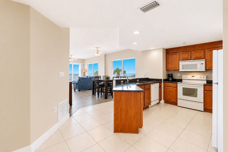 Step into an open, sunlit space where everything flows together beautifully. Your kitchen gleams with granite counters, warm wood cabinetry, and full appliances ready for your family meals.