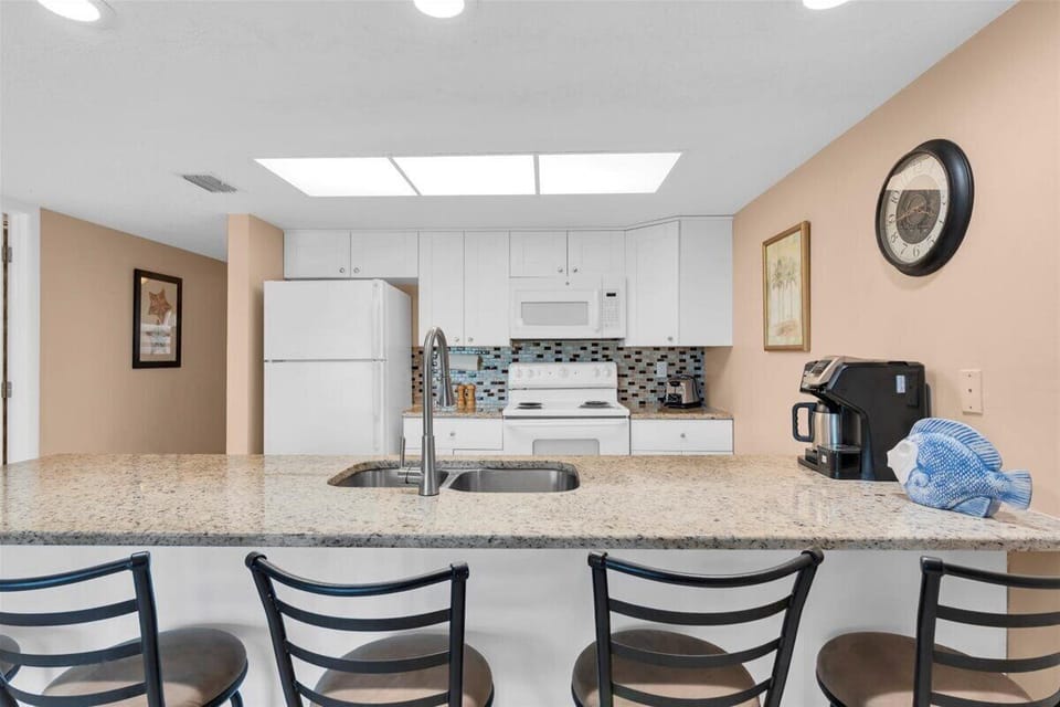 Bright skylight and granite countertops create a welcoming space for your morning coffee. The modern backsplash and open layout make meal prep effortless.