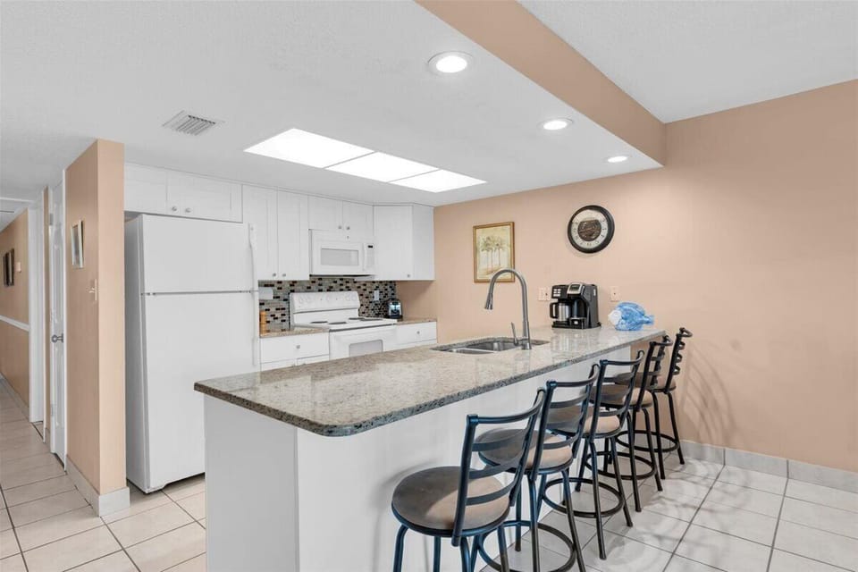 Your fully equipped kitchen features granite countertops, modern appliances, and a spacious breakfast bar with seating for four—perfect for morning coffee or casual dining together.