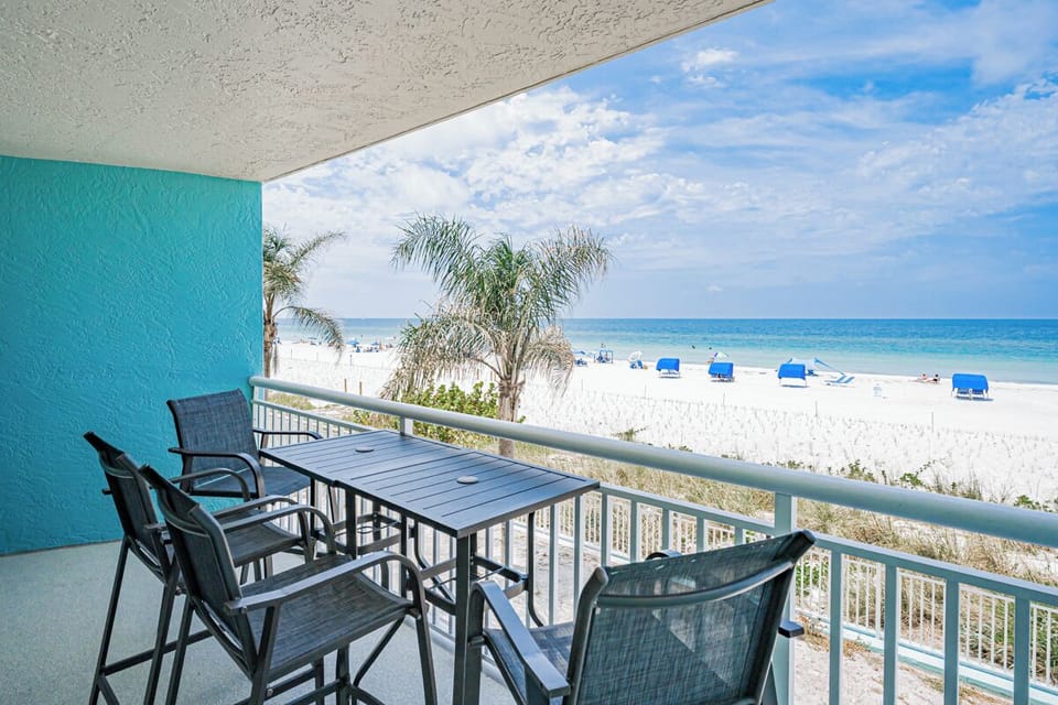 Beachfront balcony offers unobstructed views of white sand and turquoise waters, with bistro-style seating perfect for morning coffee or evening cocktails.