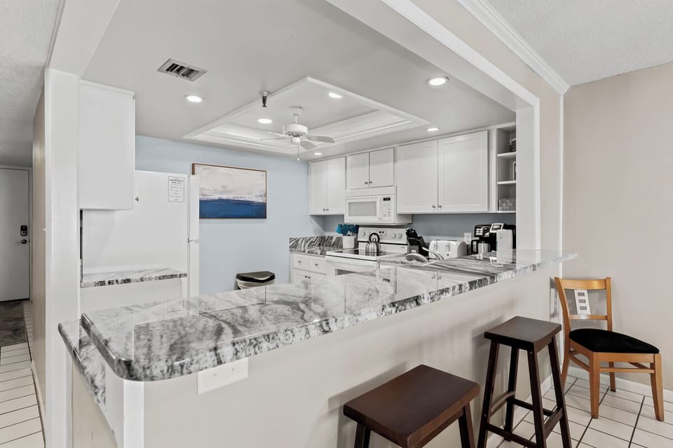 Step into your bright, open kitchen featuring sleek white cabinetry, stunning granite countertops, and a spacious breakfast bar perfect for morning coffee or casual meals.